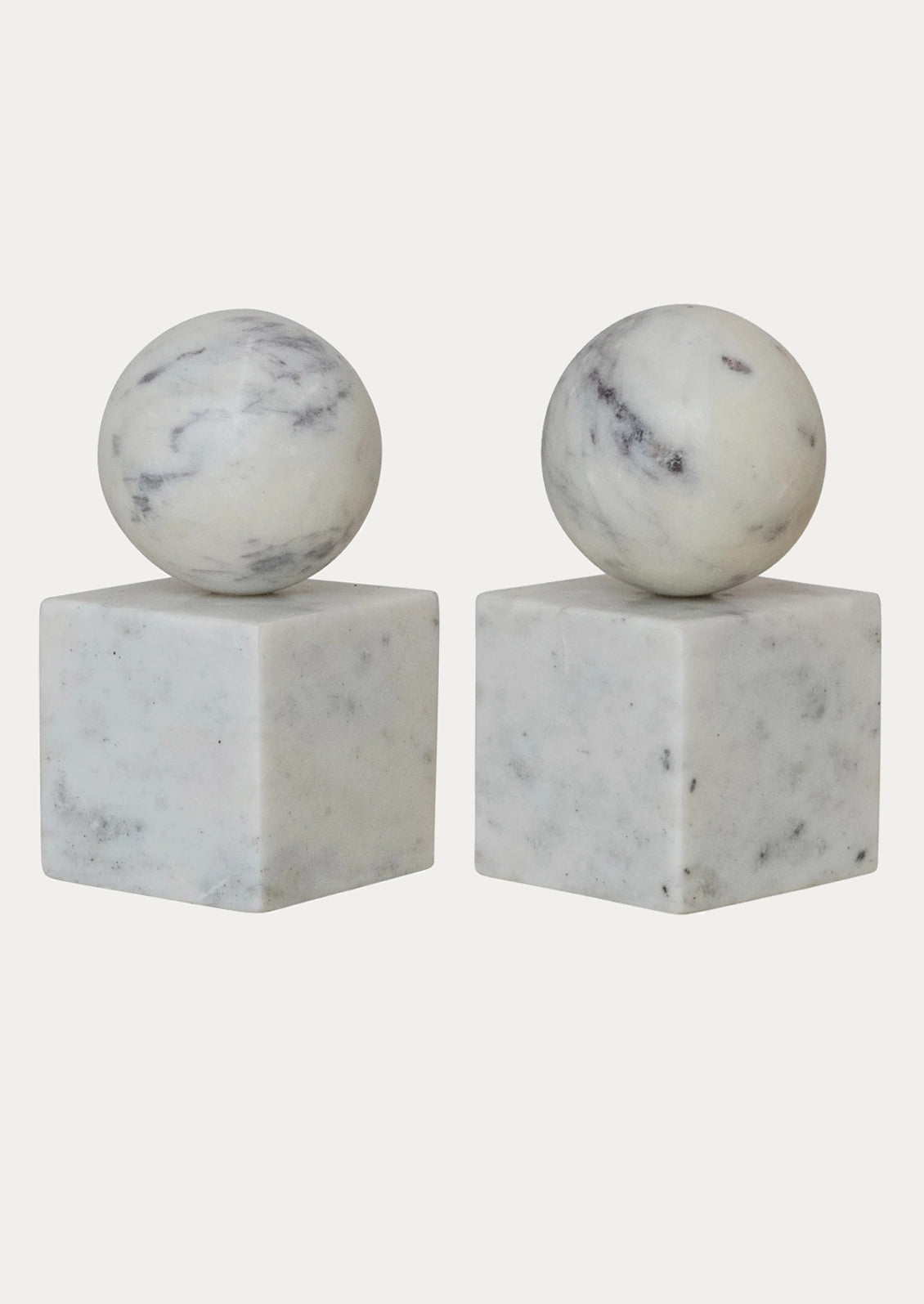 A pair of bookends in white marble with sphere on top of square base.
