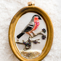 Red Bird: A glass ornament of gold frame around red bird.