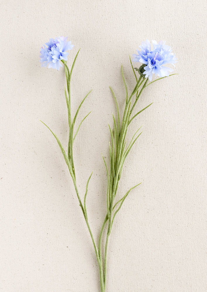 A faux bachelor's button stem with two blue flowers.