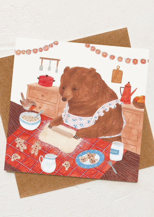 A greeting card with image of a bear baking cookies together with a small bird.