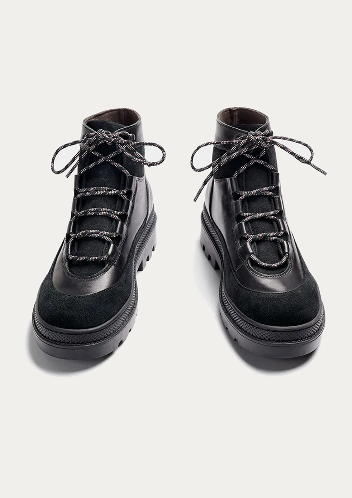Pair of black leather boots with laces on a light gray background