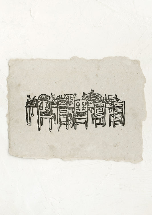 An art print made from grey handmade paper with letterpressed image of a dining table with chairs.