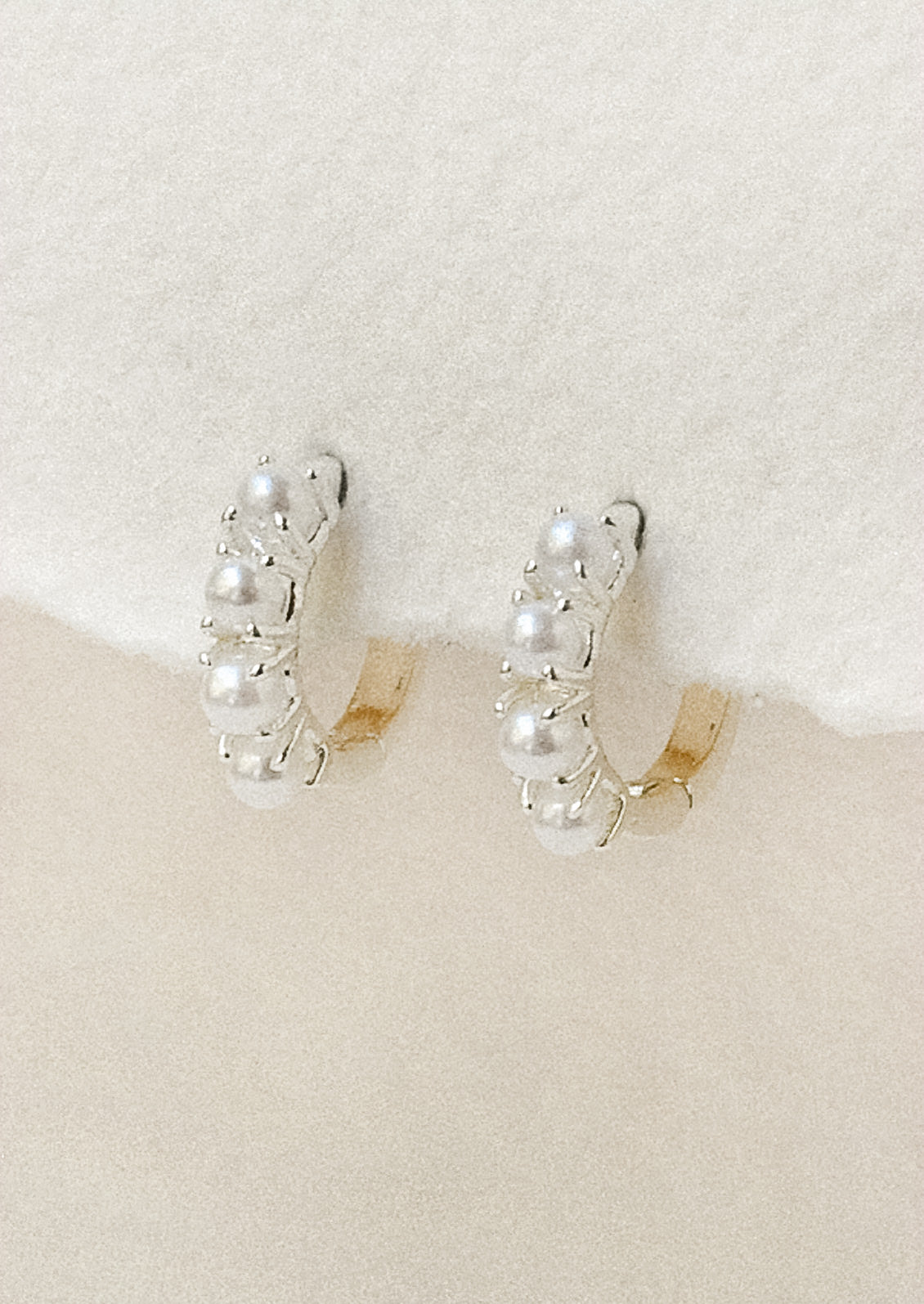 A pair of sterling silver huggie hoop earrings adorned with imitation pearls 