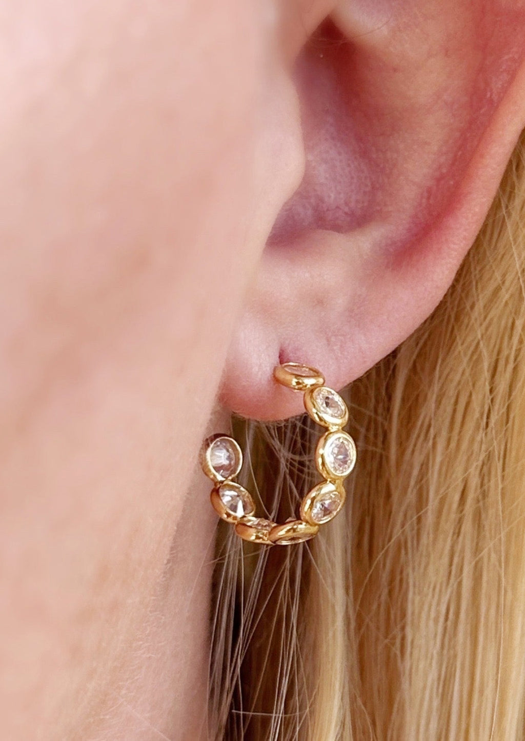 2: A pair of gold hoop earrings with clear bezeled circles.