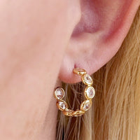 2: A pair of gold hoop earrings with clear bezeled circles.