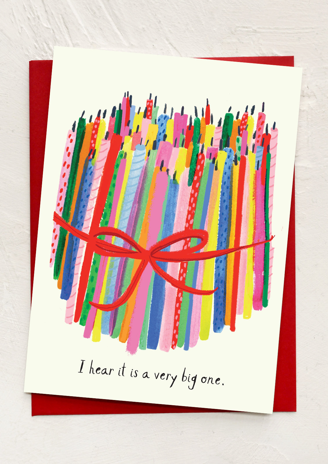 Greeting card with colorful striped candles and a red bow on a white background