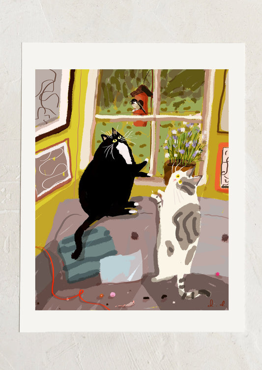 An art print of an illustration of two cats watching a bird outside a window.