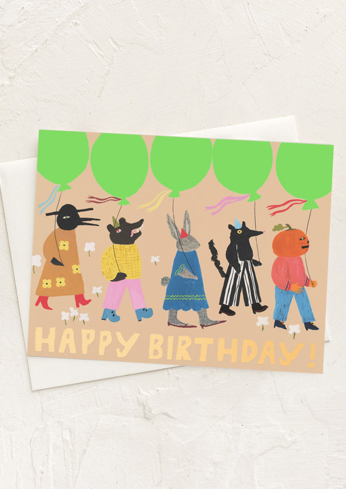 A card with illustration of strange creatures in a parade with balloons, text reads "Happy birthday!".