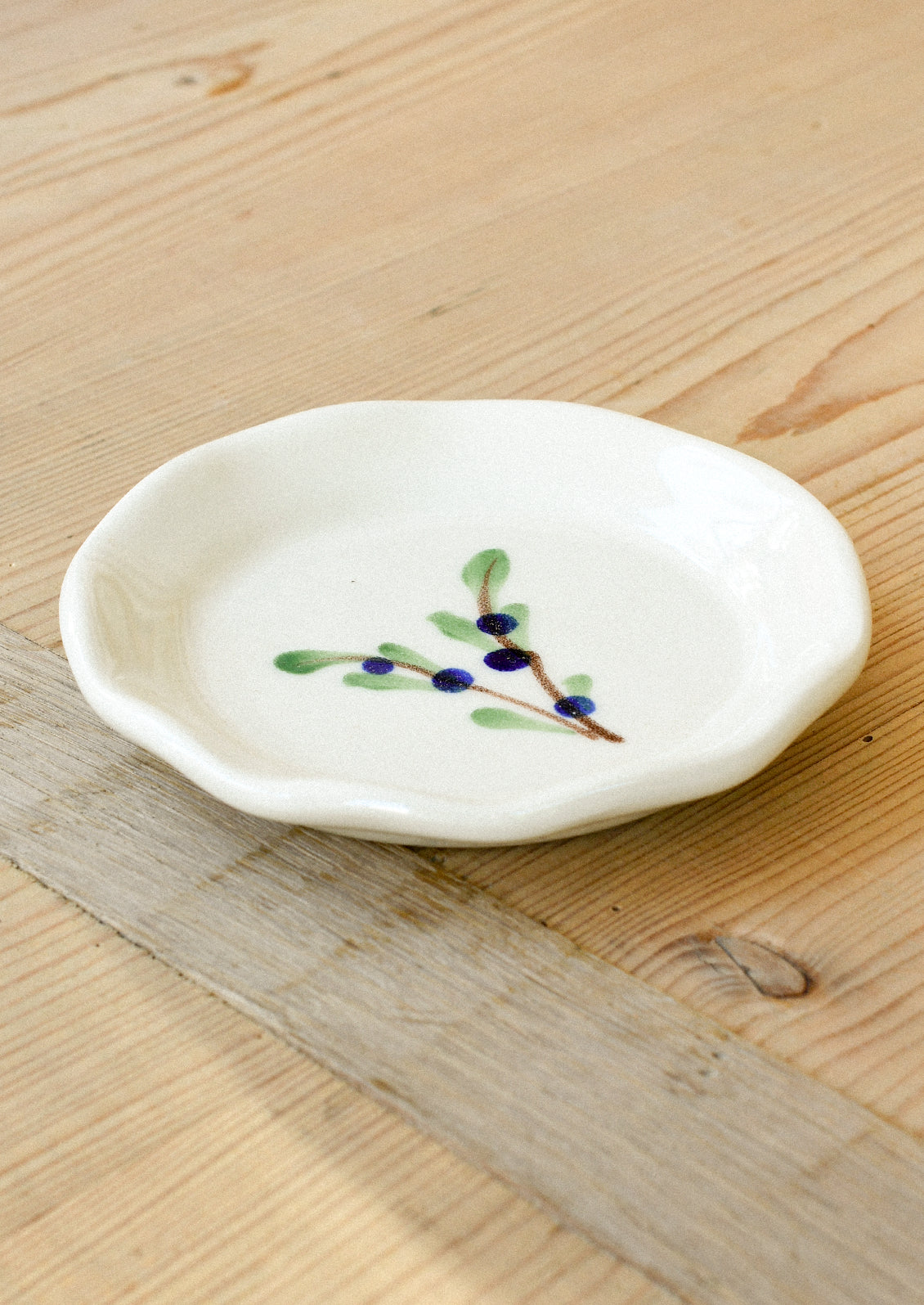 A small ceramic dipping fish with a watercolor illustration of blueberries on leafy branches in the center.