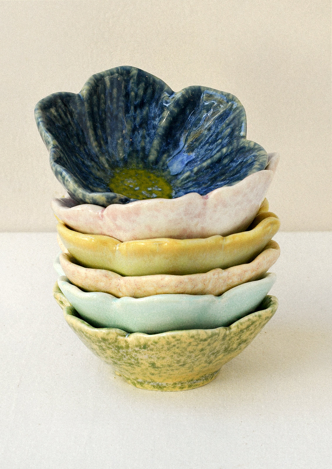 A stack of small flower shaped catchall bowls in various colors.