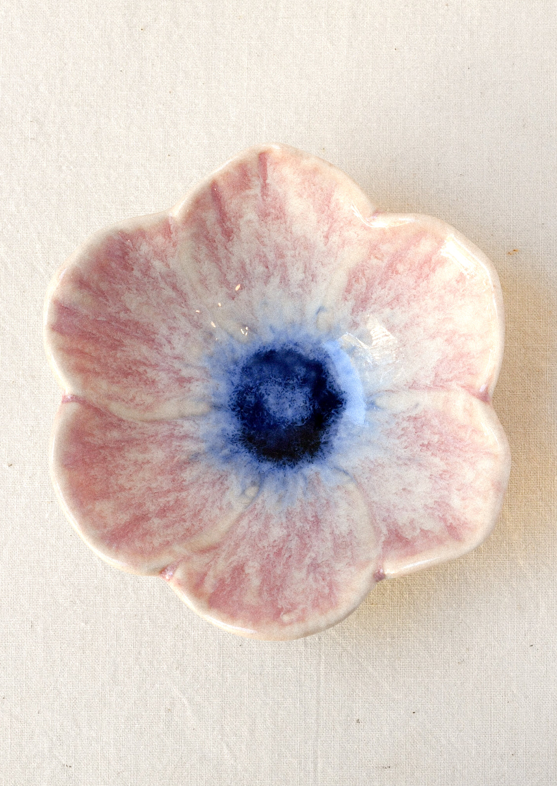 A small ceramic catchall bowl in the shape of a six petal flower in pink with a navy center.