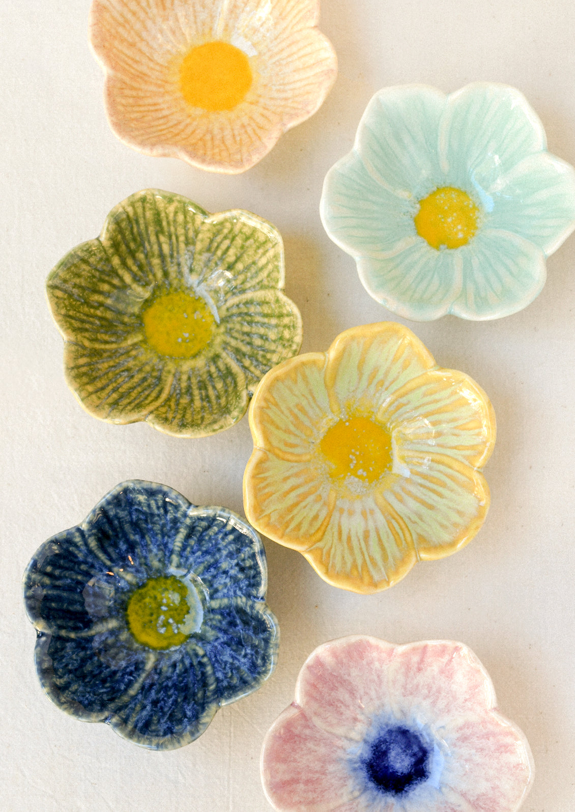 An assortment of small flower shaped catchall bowls in various colors.