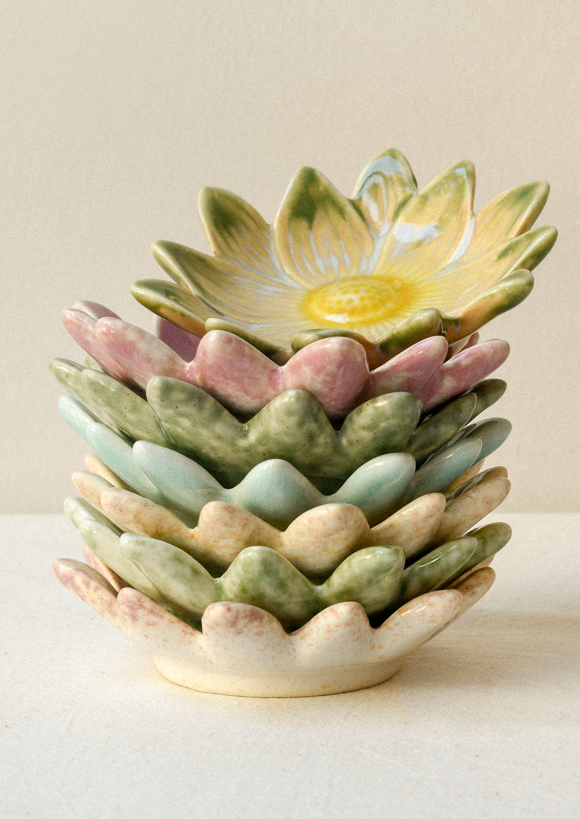 A stack of small flower shaped catchall plates in various colors.