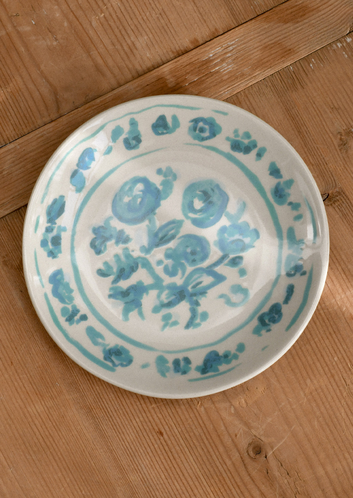 White plate with aqua floral patterns on a wooden surface