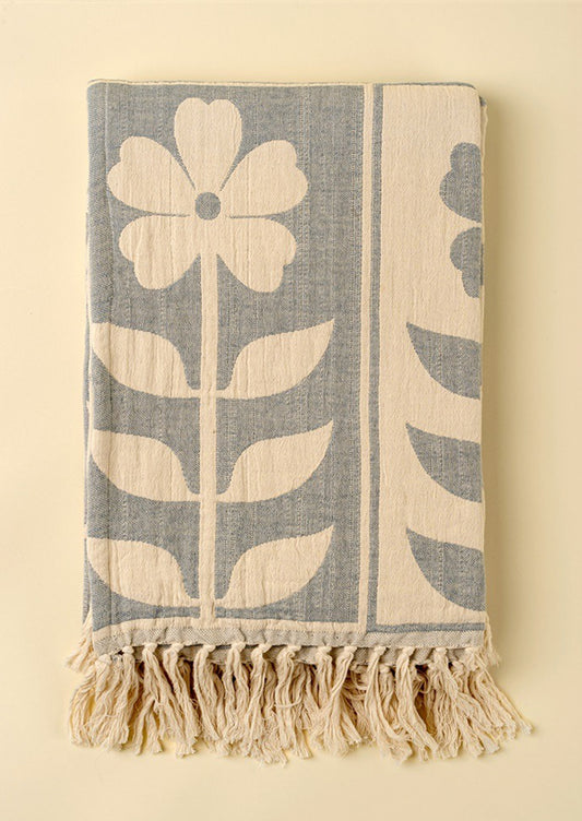 Floral patterned throw in blue and cream with tassel trim.