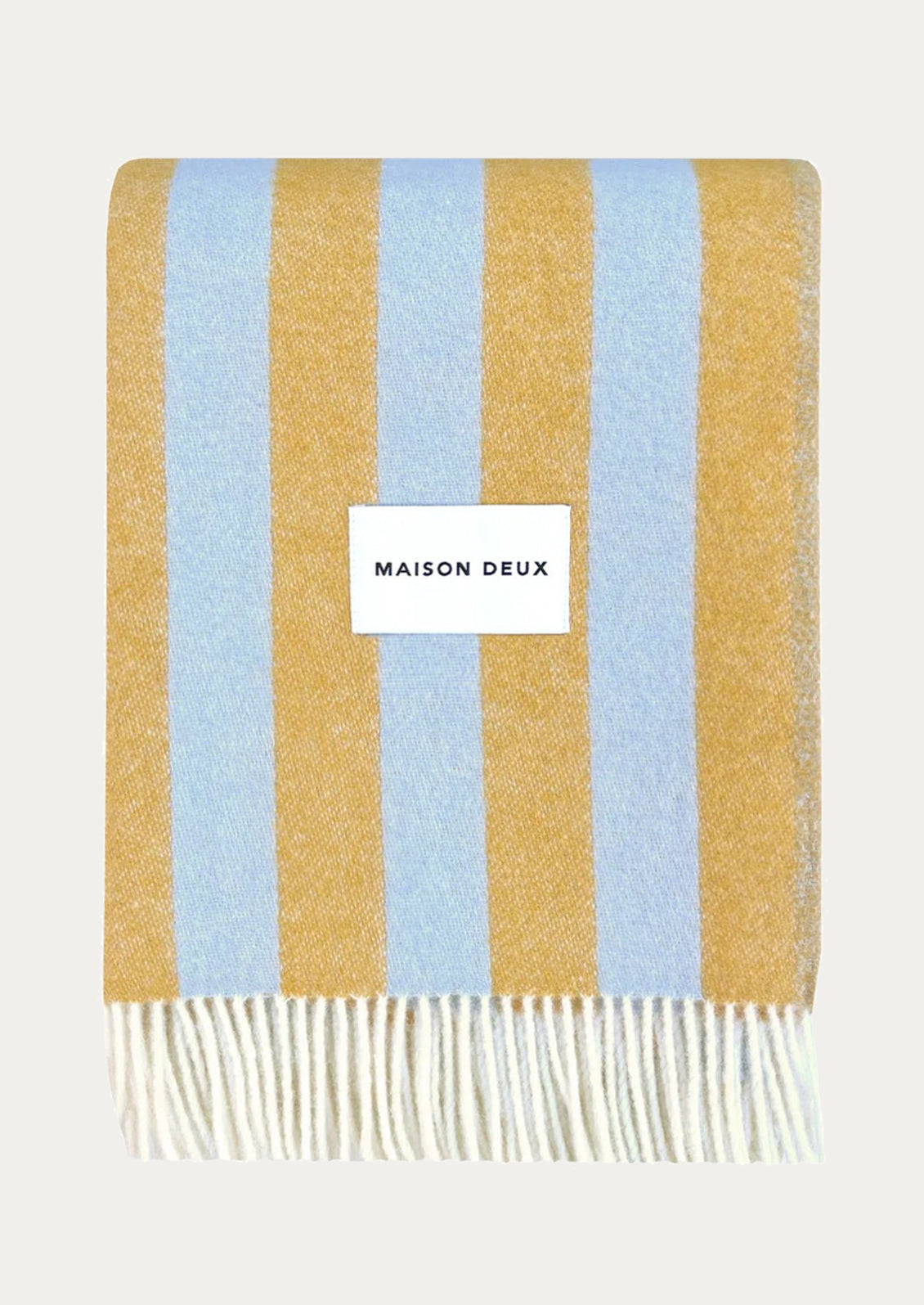 Striped blanket in light blue and honey with 'Maison Deux' label.
