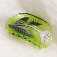 Green / Lily: A transparent green curved shape hair claw with lily design.
