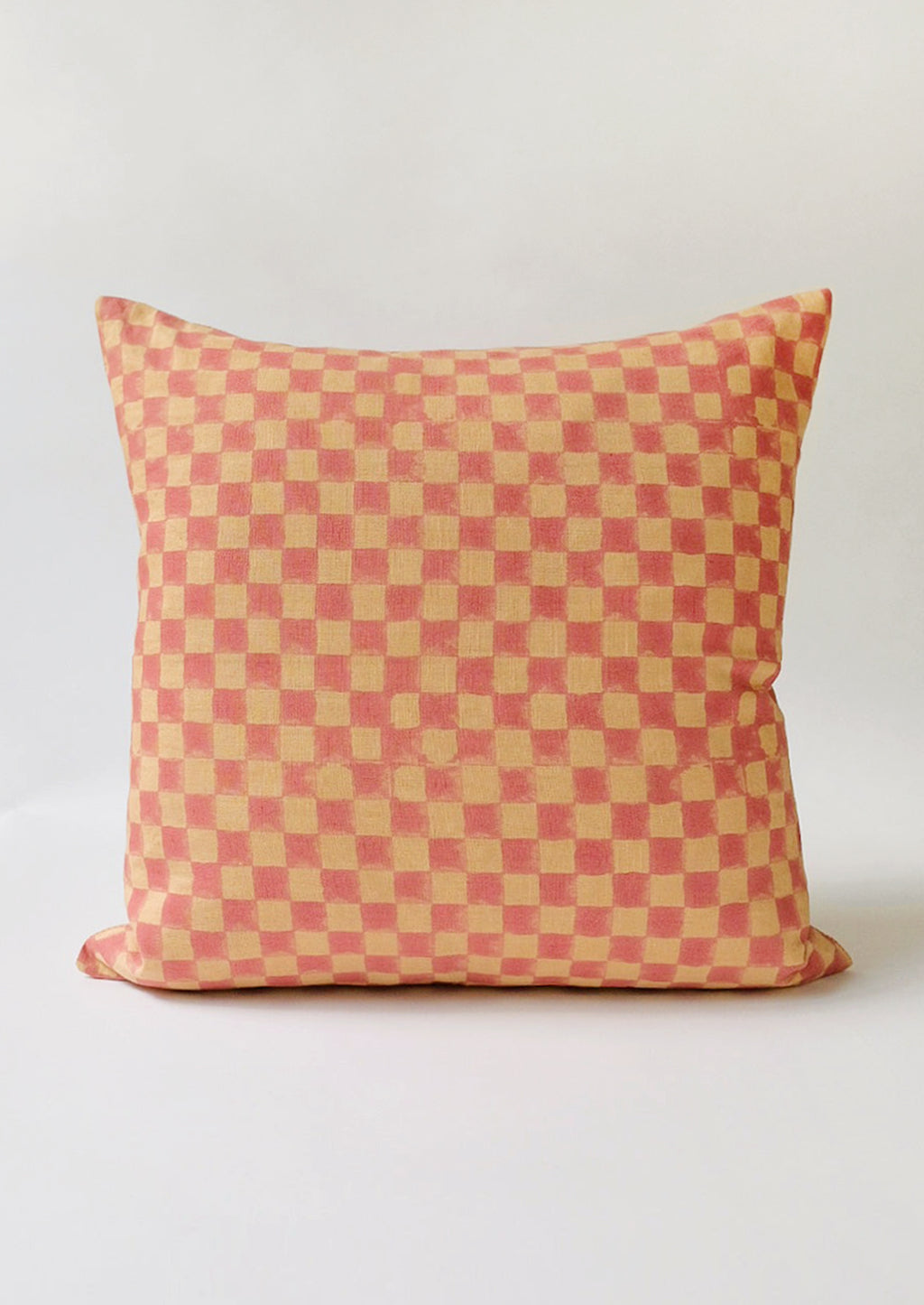 2: A block printed linen pillow in sand with pink checker print.