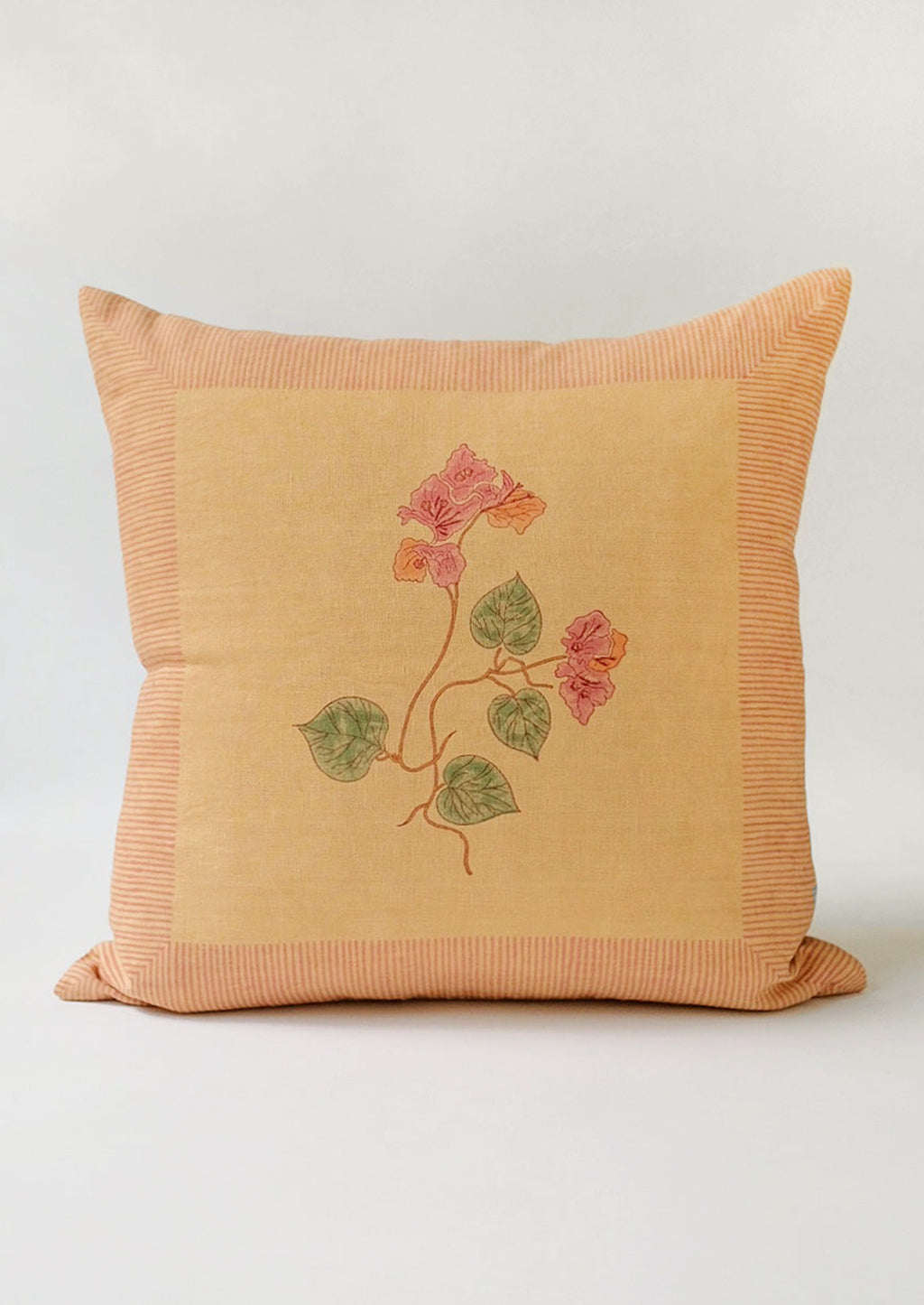 1: A block printed linen pillow in sand with pink bougainvillea print.