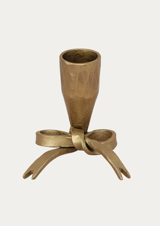 A brass-tone metal candleholder with bow shape base.
