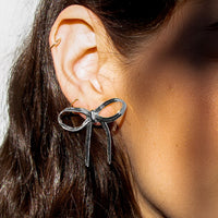 Silver / Short: A bow shaped earring made of silver snake chain material.