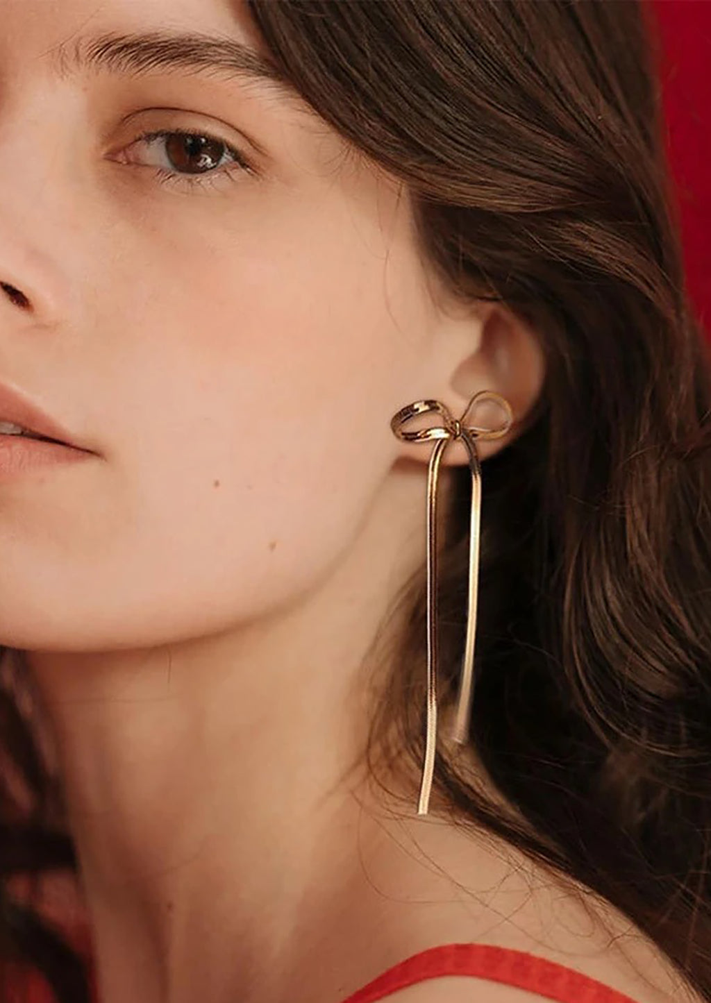 Gold / Long: A bow shaped earring made of gold snake chain material.