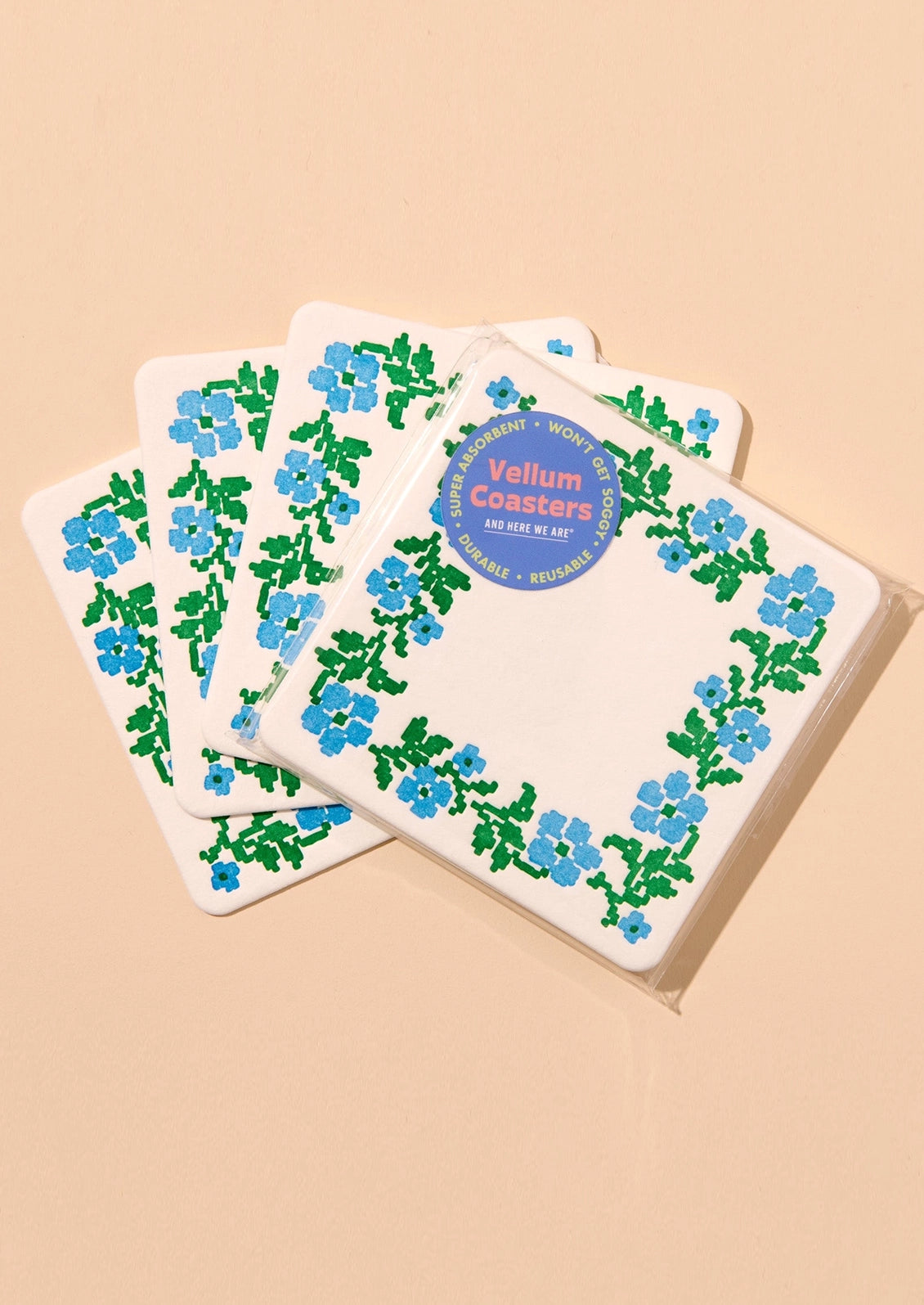  A set of paper coasters with blue and green needlepoint floral pattern.