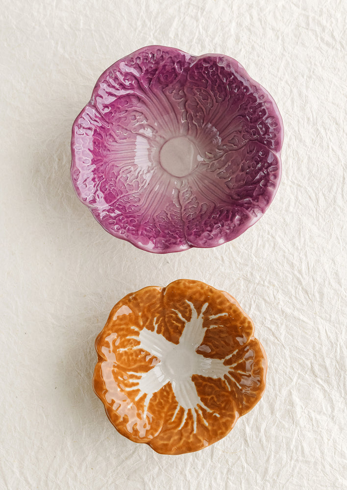 A pair of ceramic nesting bowls that look like orange and purple cabbage.