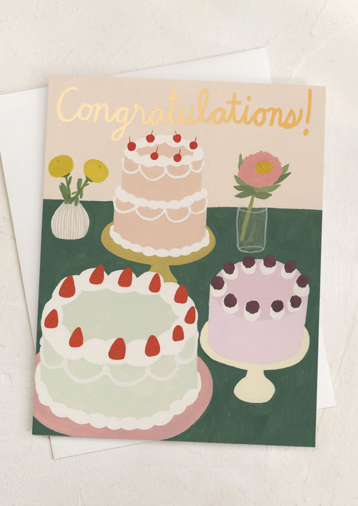A greeting card with illustration of cakes on cake stands with flowers, text reads "Congratulations!".
