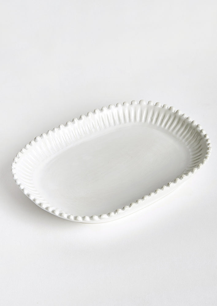 A rectangular ceramic platter in white with rounded edges and hobnail pleated border.