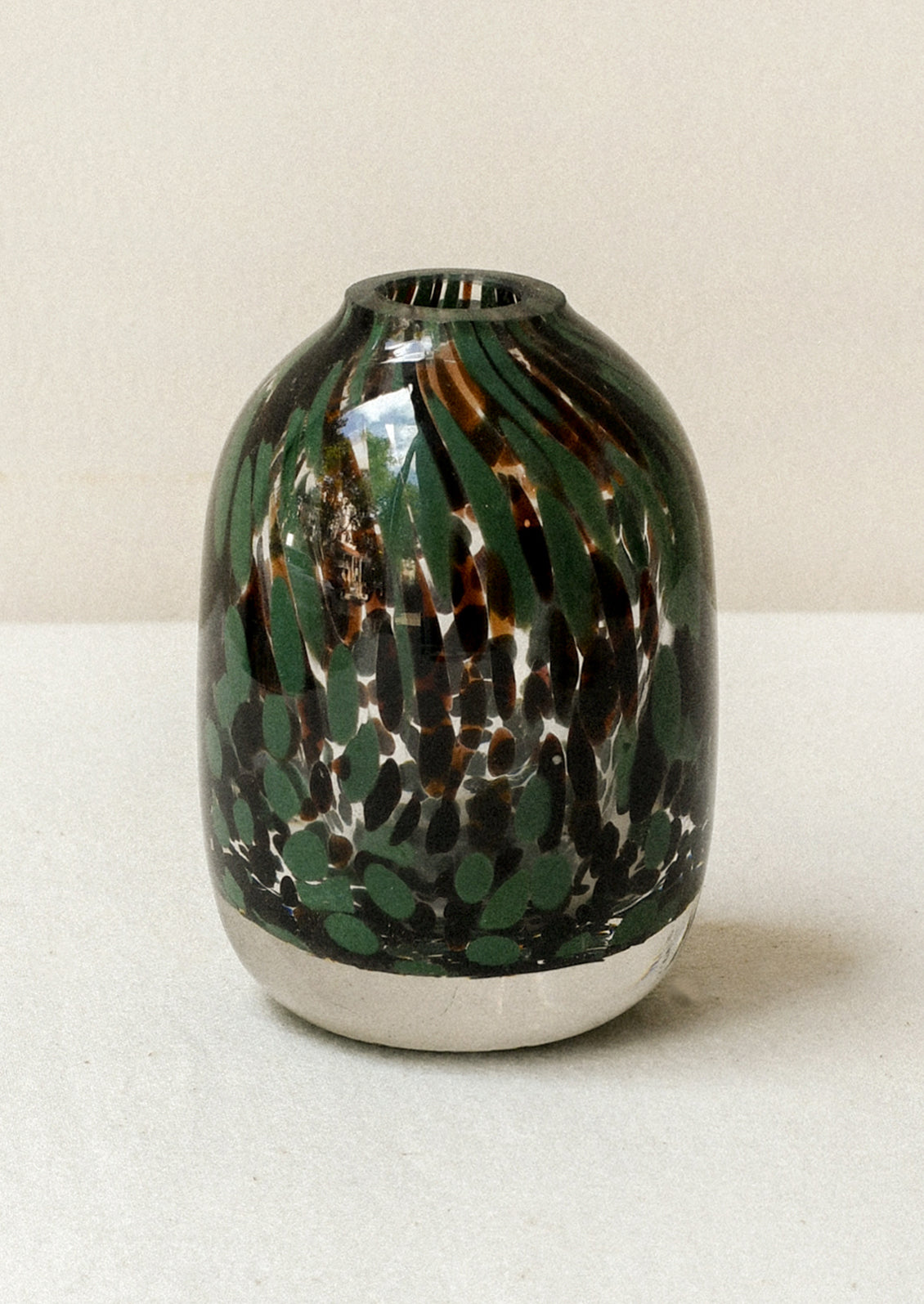 A small glass bud vase with a dark green and dark brown painted design.
