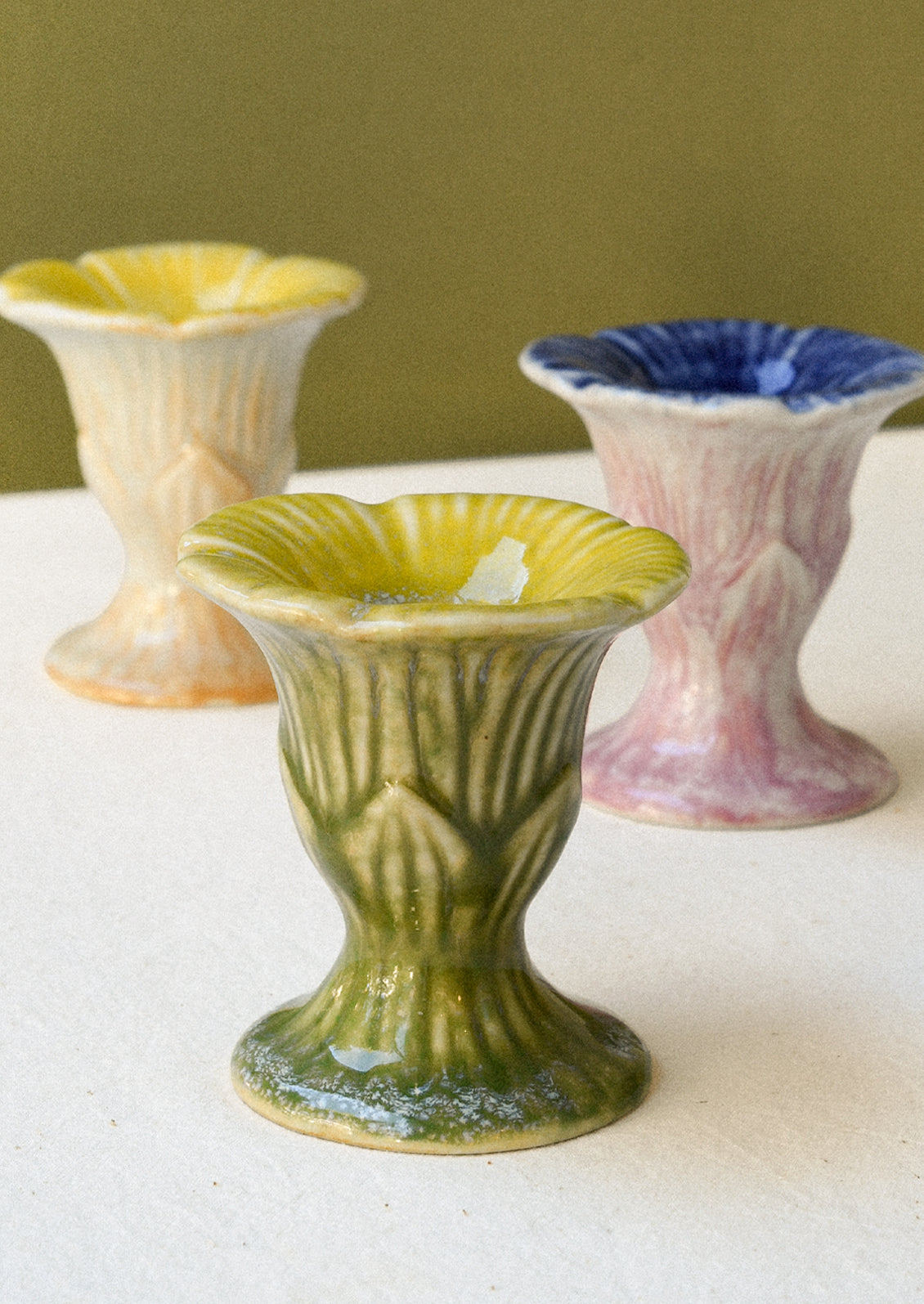 Three colorful flower-shaped ceramic taper candle holders.