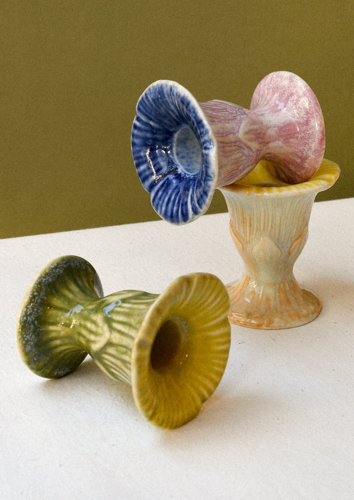 Three colorful flower-shaped ceramic taper candle holders.