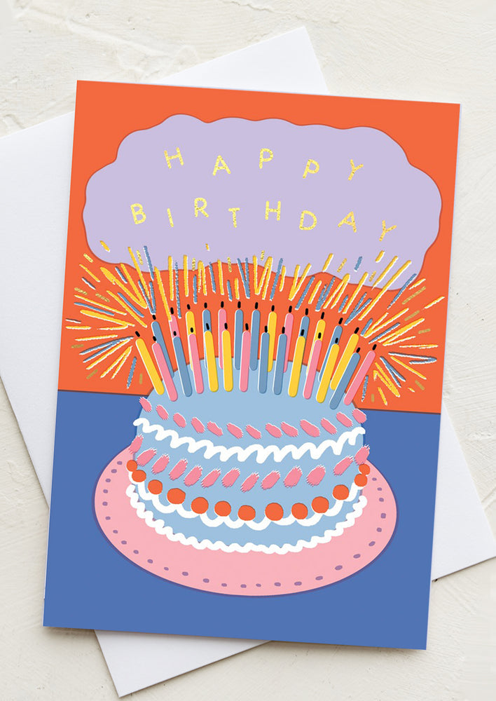 Orange and blue colorful card reading "Happy birthday" on cake with lots of candles.