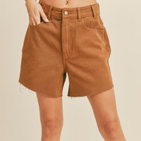 1: A woman in light brown denim shorts. 
