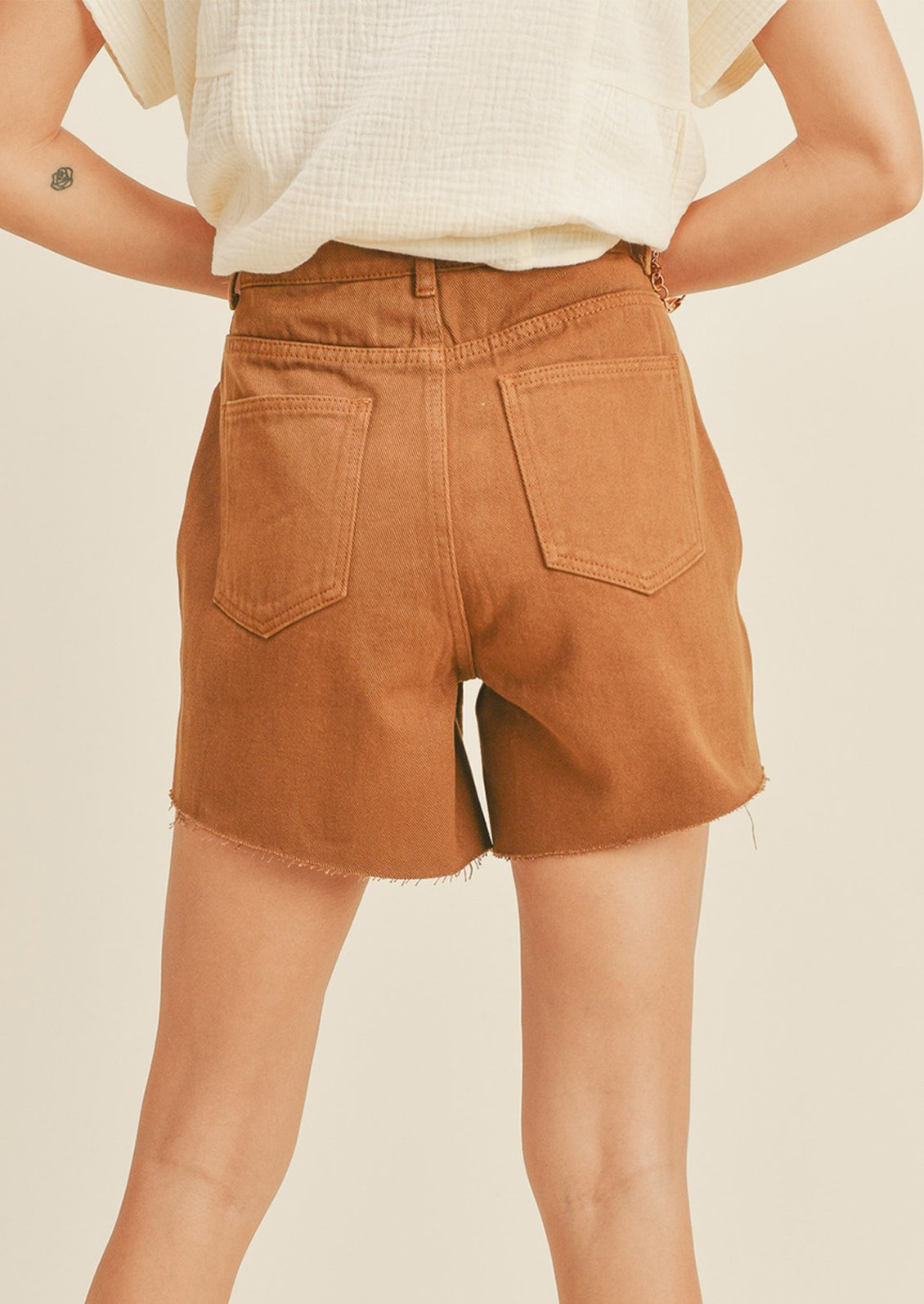 A woman in light brown denim shorts, seen from behind. 