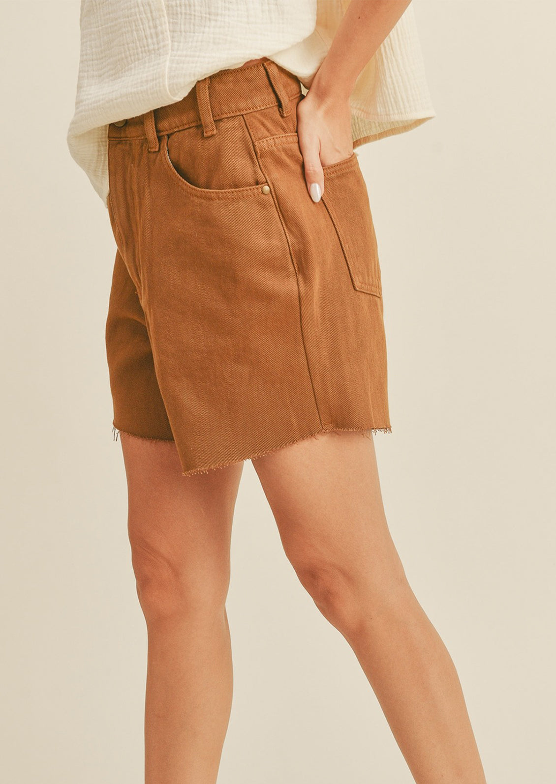 A woman in light brown denim shorts, seen from the side. 