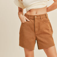 3: A woman in light brown denim shorts. 