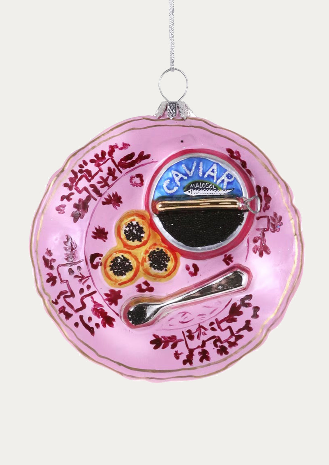 Decorative ornament resembling a pink plate with caviar and a spoon on a white background