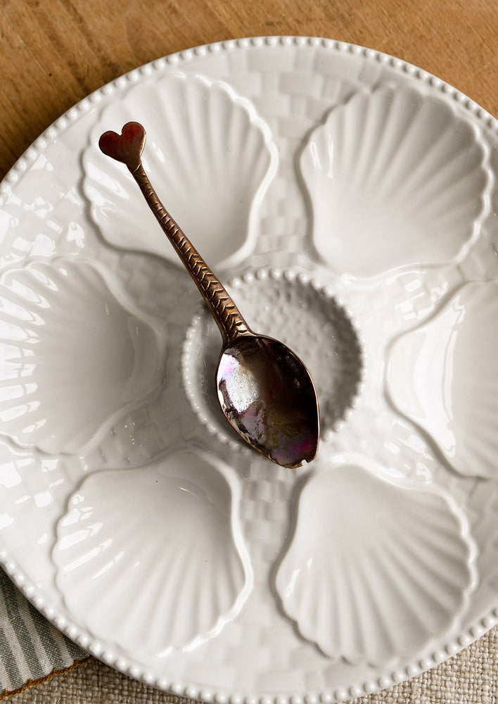 A glossy white ceramic plate with shell design.