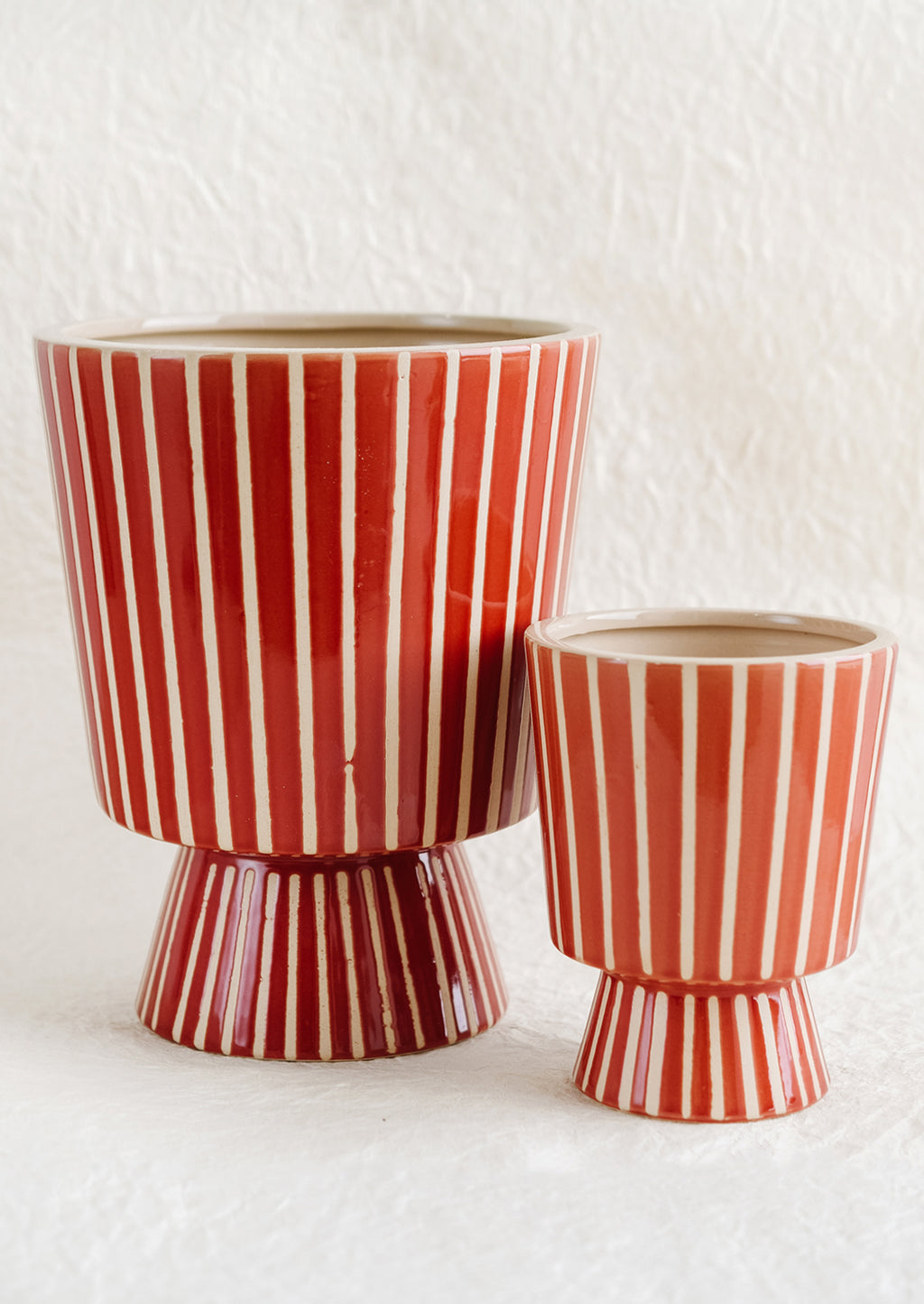 2: A footed planter with vertical white stripes on red ceramic, in small and large sizes.