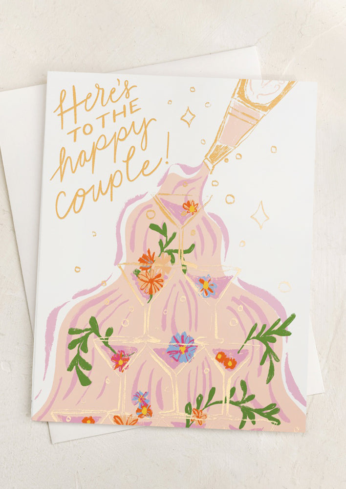 A greeting card with illustration of champagne tower, text reads "Here's to the happy couple!".
