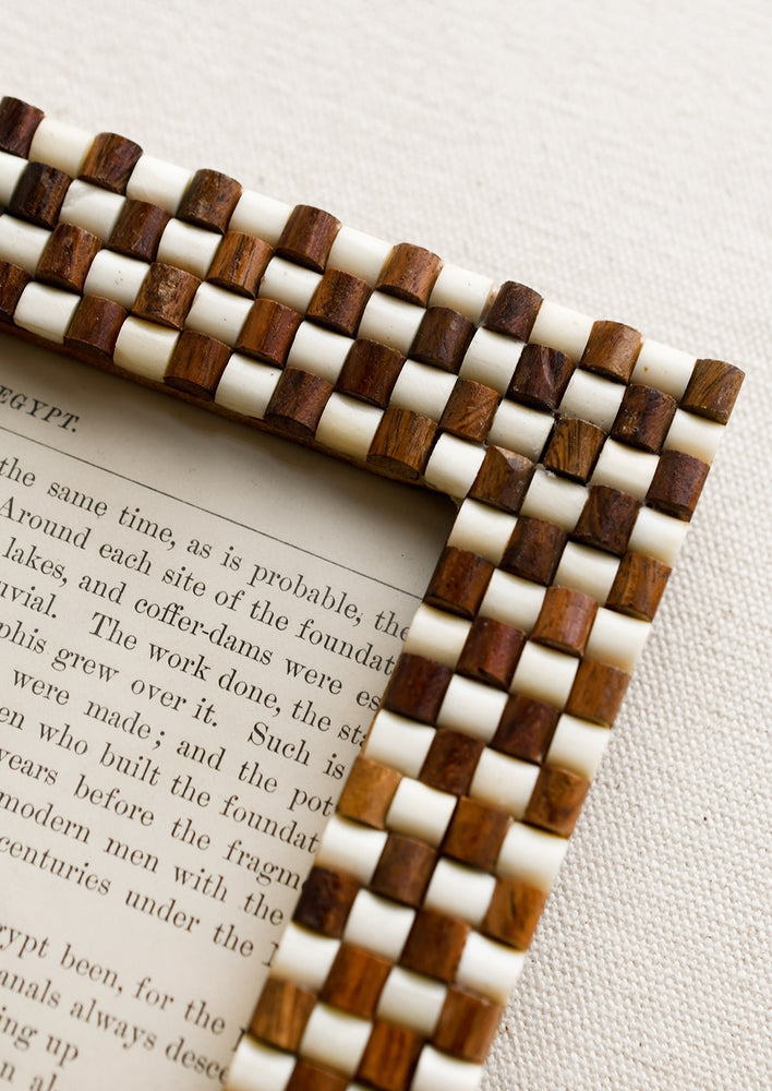 A picture frame with textural raised brown and white checker weave pattern.