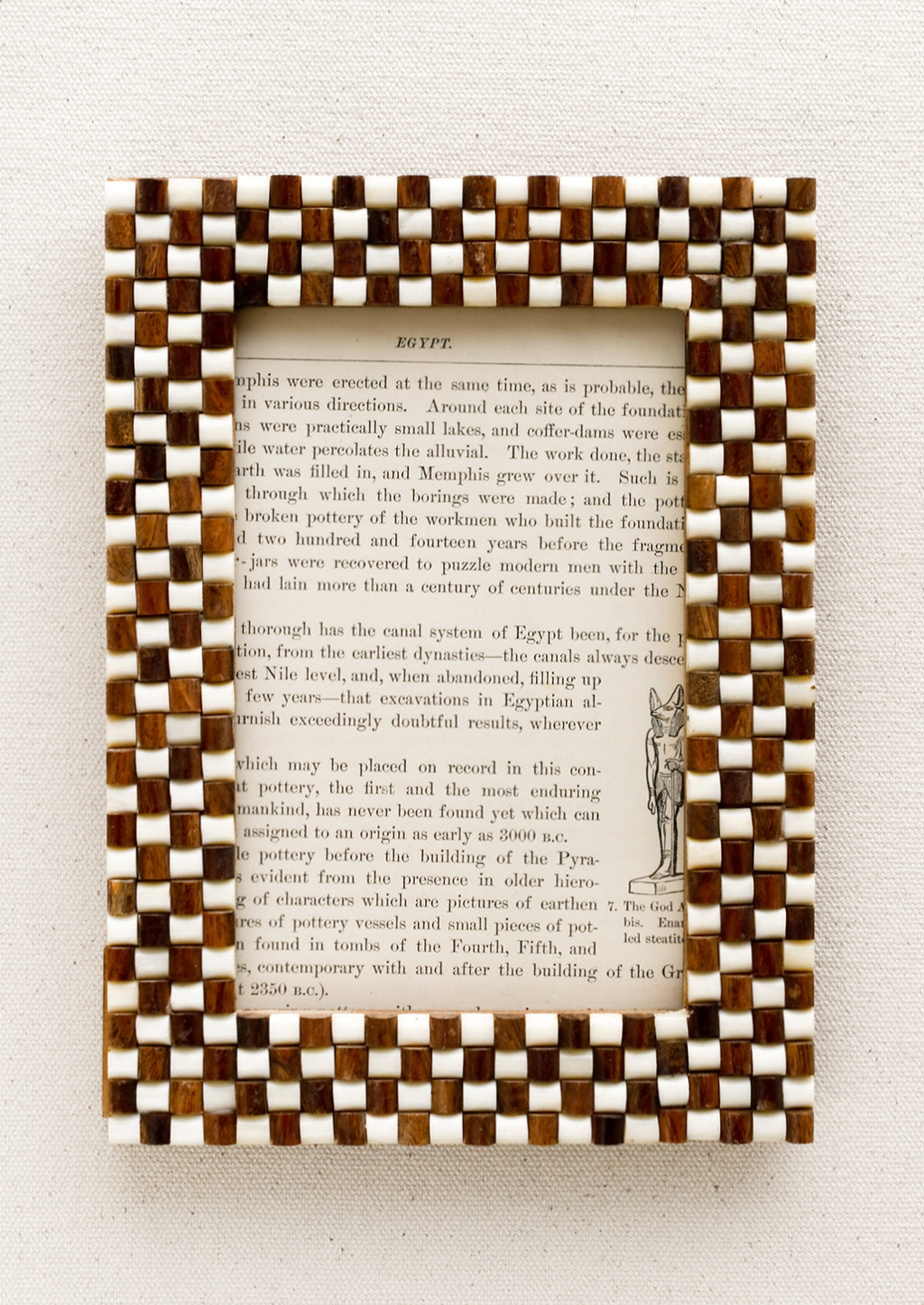 1: A picture frame with textural raised brown and white checker weave pattern.