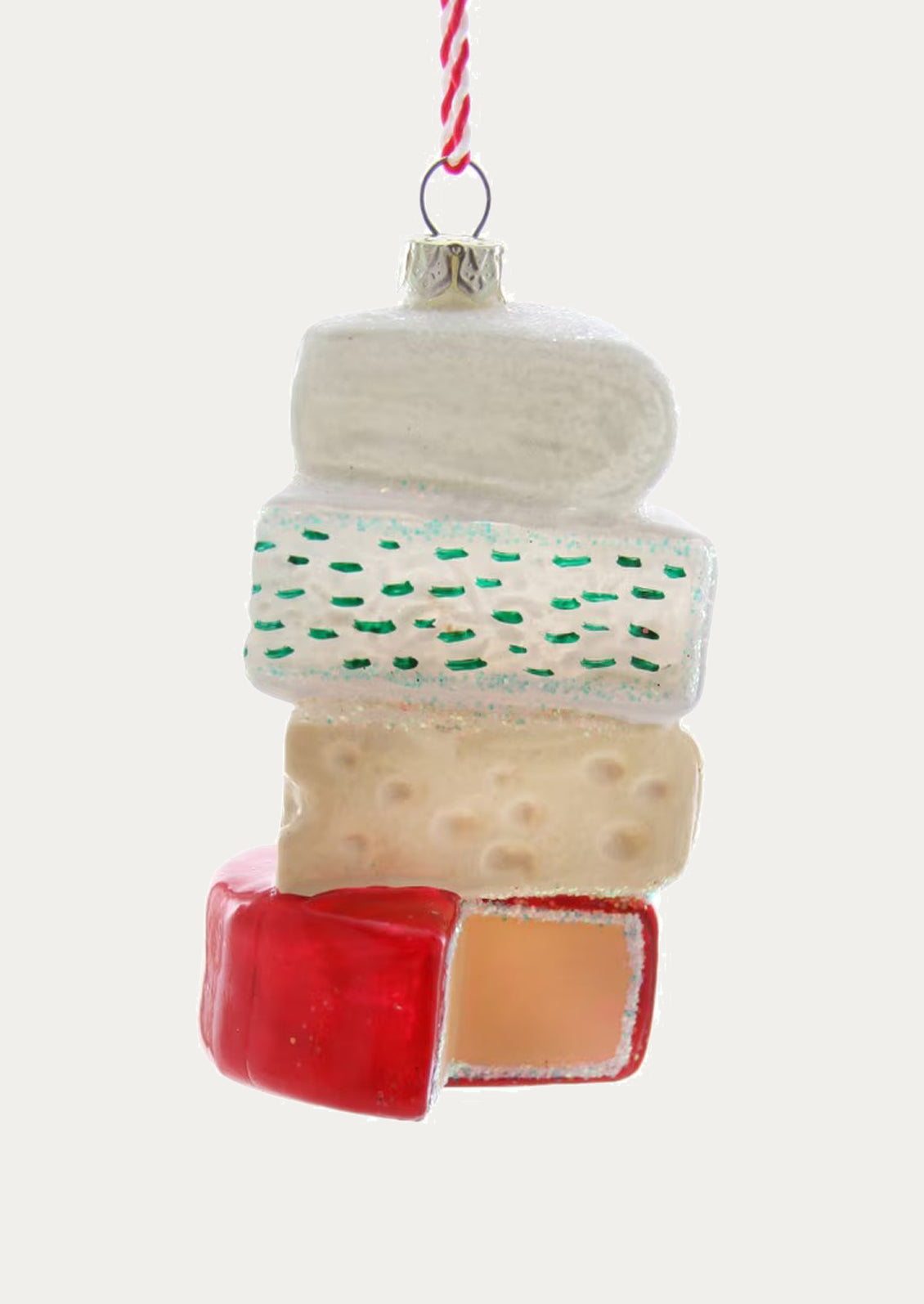 A glass ornament depicting a stack of different cheeses.