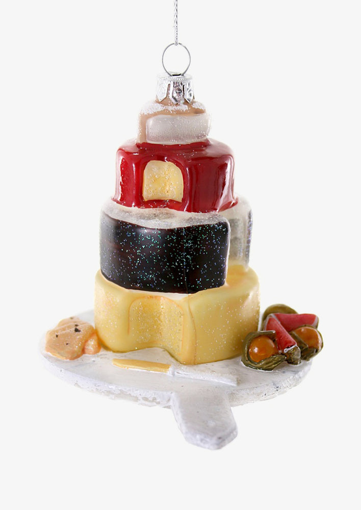 An ornament of a tower of cheese on a platter.