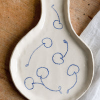 1: A handmade ceramic spoon rest with hand-drawn cherries in blue.