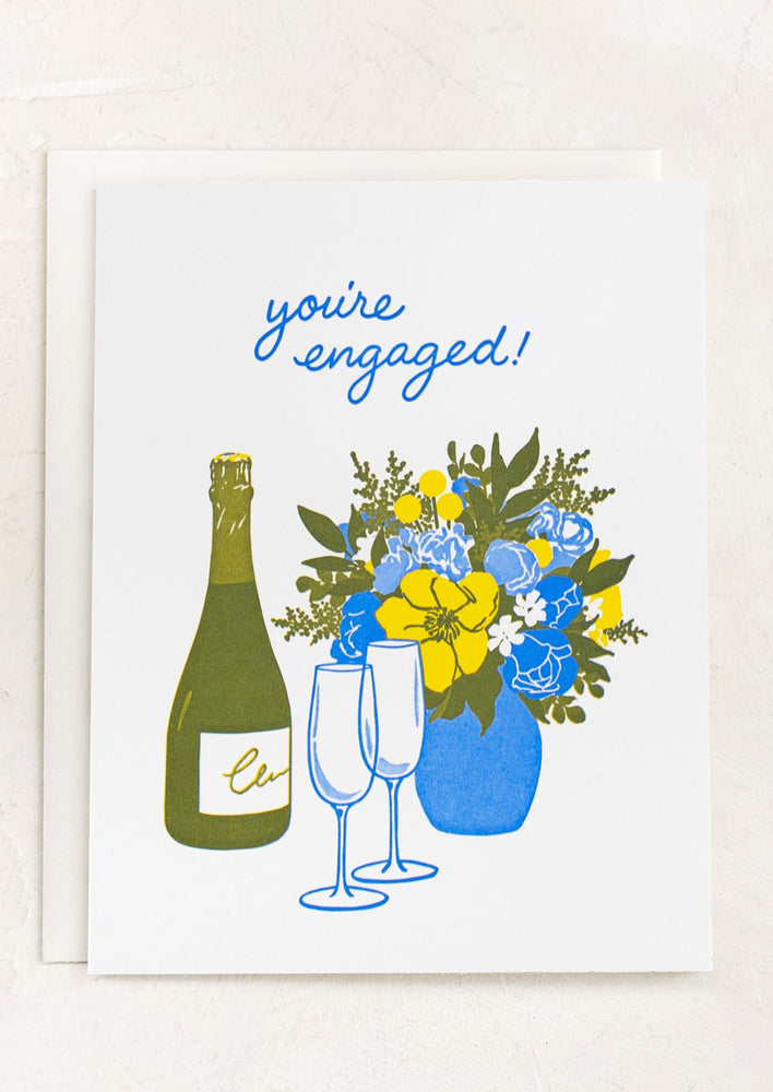 A card with illustration of champagne and flowers, text reads "You're engaged!".