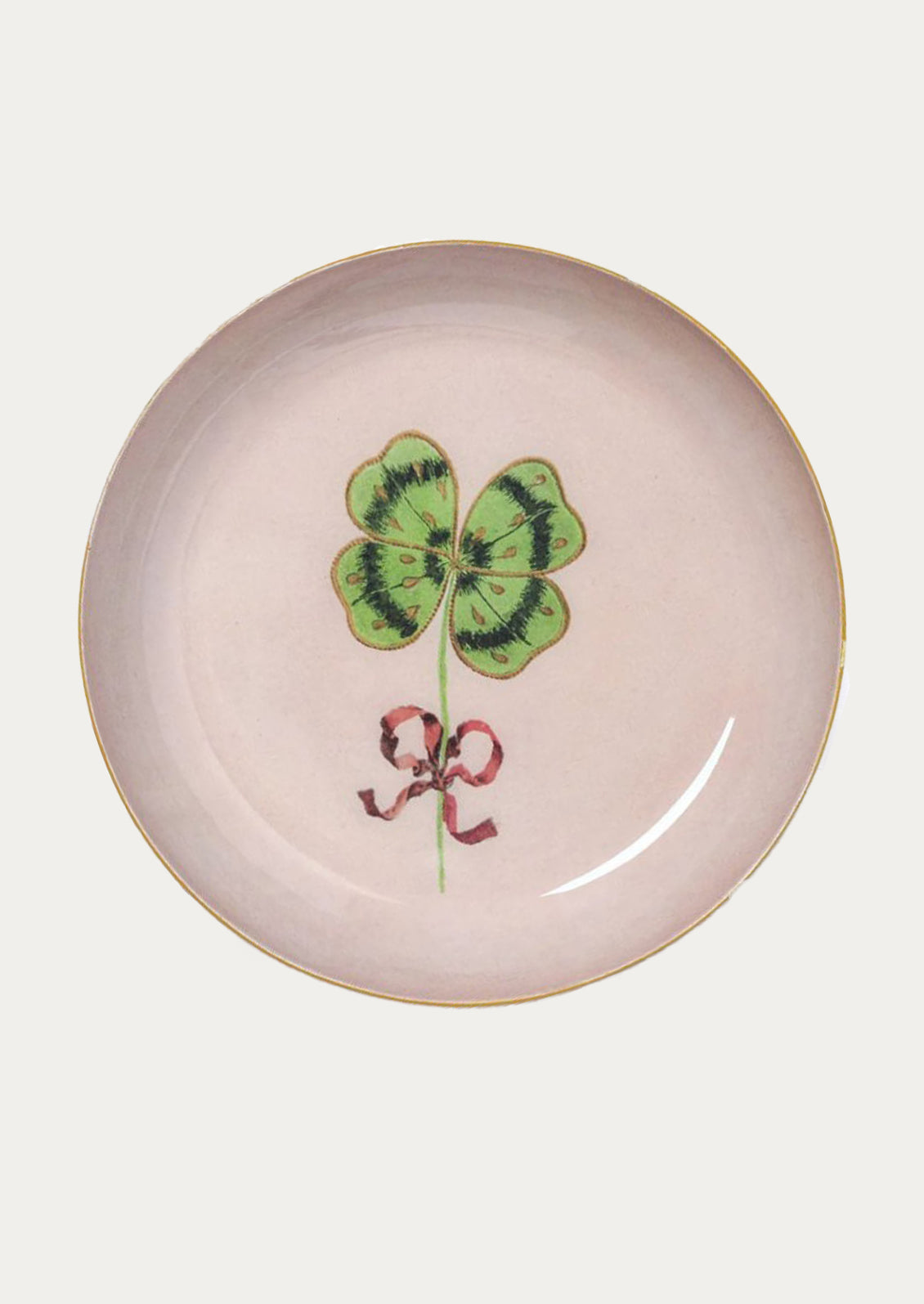 Decorative round tray with a four-leaf clover and ribbon design on a light pink background