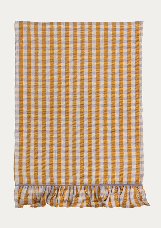 A two-tone gingham tea towel in orange and lavender with ruffle trim on bottom.